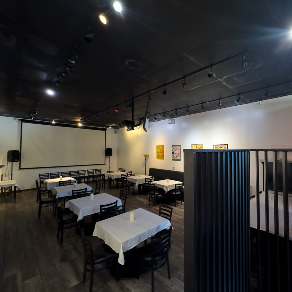 Dining room at Pizzeria Vivoli with tables, chairs, a large projection screen, and modern decor.