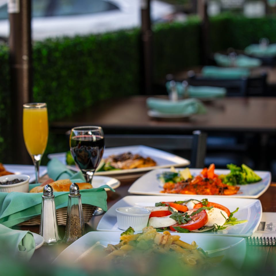Italian dishes, including pasta, Caprese salad, and seafood, served on an outdoor patio at Pizzeria Vivoli.