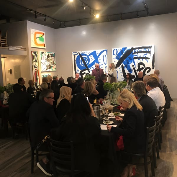 Guests seated at a long table with black tablecloths, enjoying a meal at Pizzeria Vivoli & Italian Grill.
