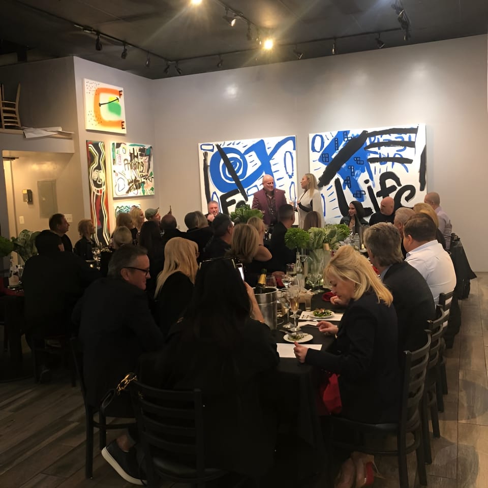 Guests seated at a long table with black tablecloths, enjoying a meal at Pizzeria Vivoli & Italian Grill.